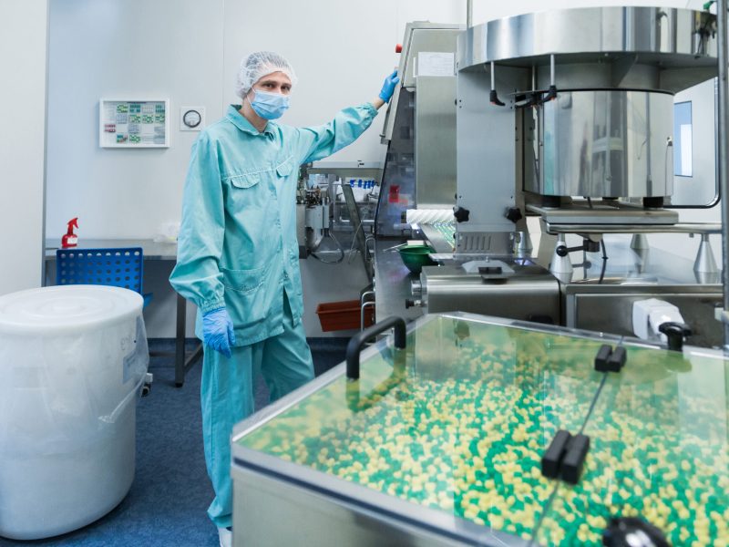 Pharmaceutical technician in sterile environment working on production of pills at pharmacy factory